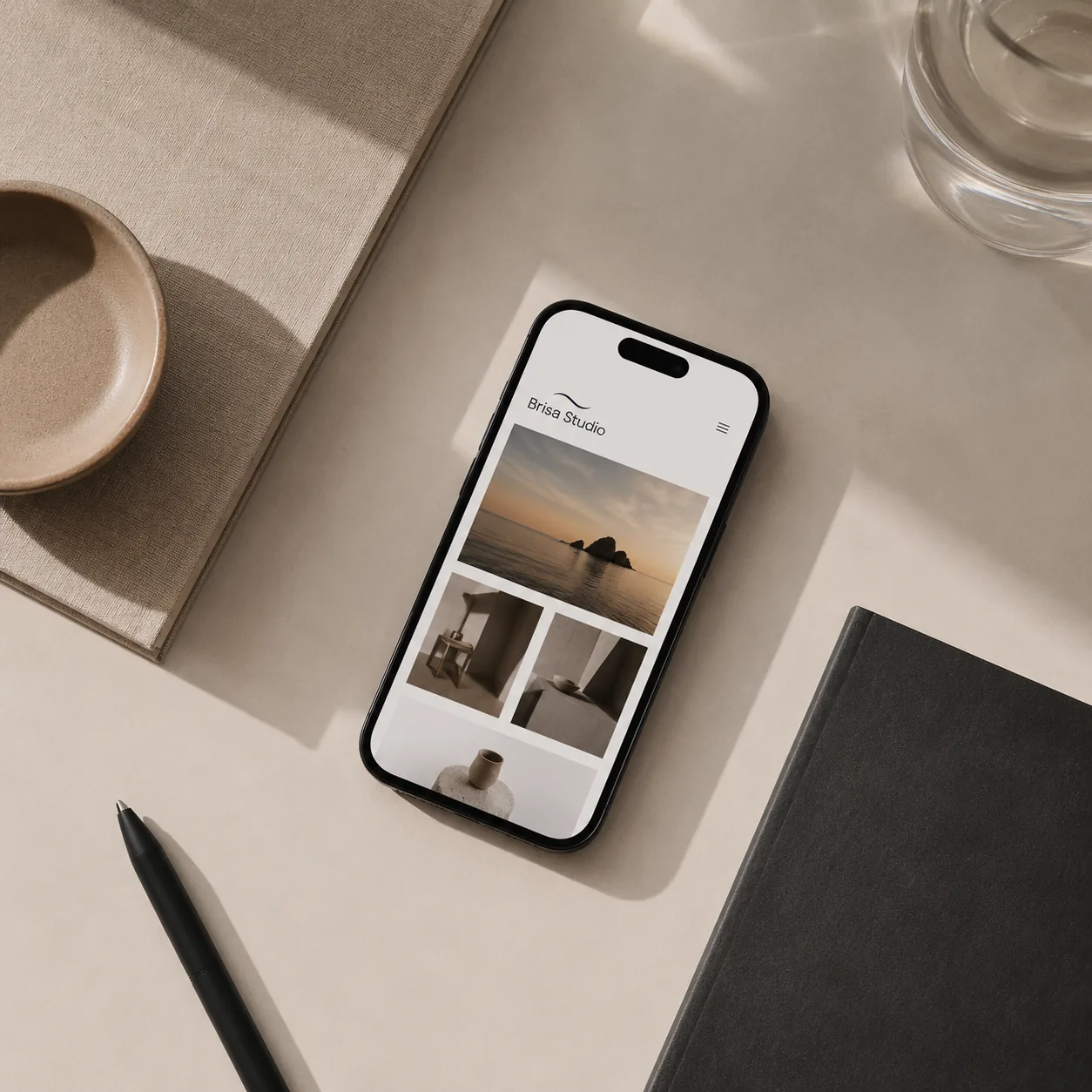 Smartphone som visar Brisa Studios hemsida på ett ljust skandinaviskt skrivbord